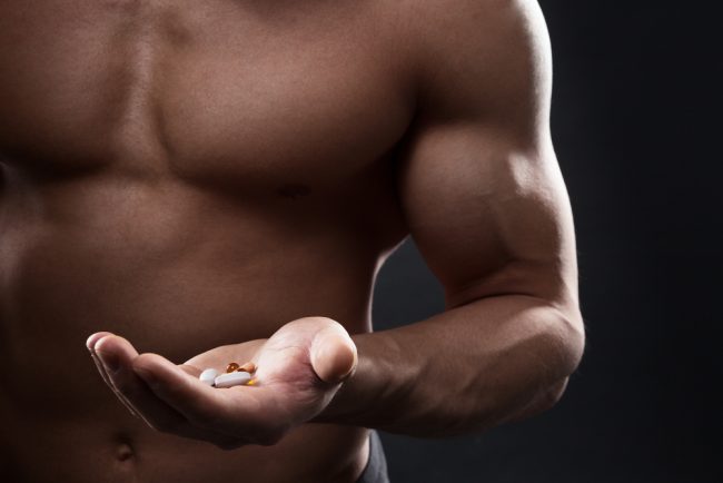 muscular man holding supplements