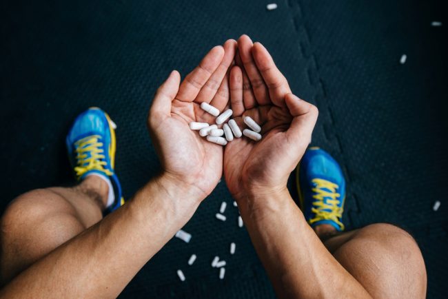 man taking pills in gym