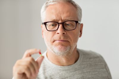 old man holding pill